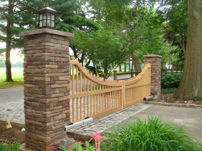 Custom Automated Clear Cedar Picket Double Gates Hung Between Stone Columns
